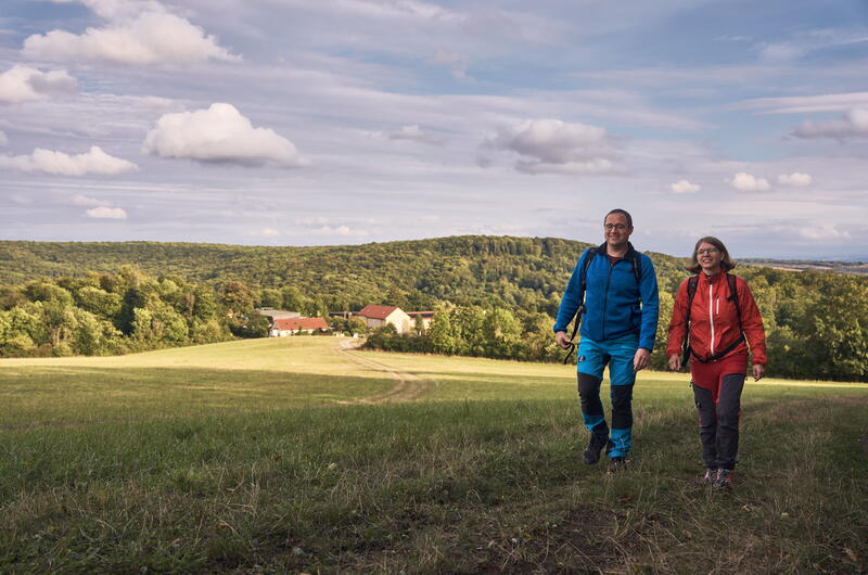 Wanderer am Harsberg, im Hintergrund ist die Jugendherberge Urwald Life Camp zu sehen