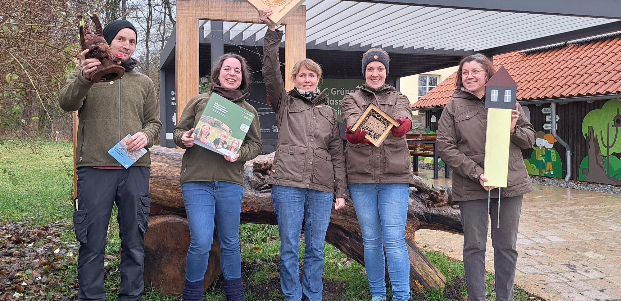 Eine Gruppe von fünf Mitarbeiter des Naturparks Eichsfeld-Hainich-Werratal posiert stolz mit dem Qualitätssiegel 'Bildung für nachhaltige Entwicklung' (BNE) vor dem Naturparkzentrum Fürstenhagen.