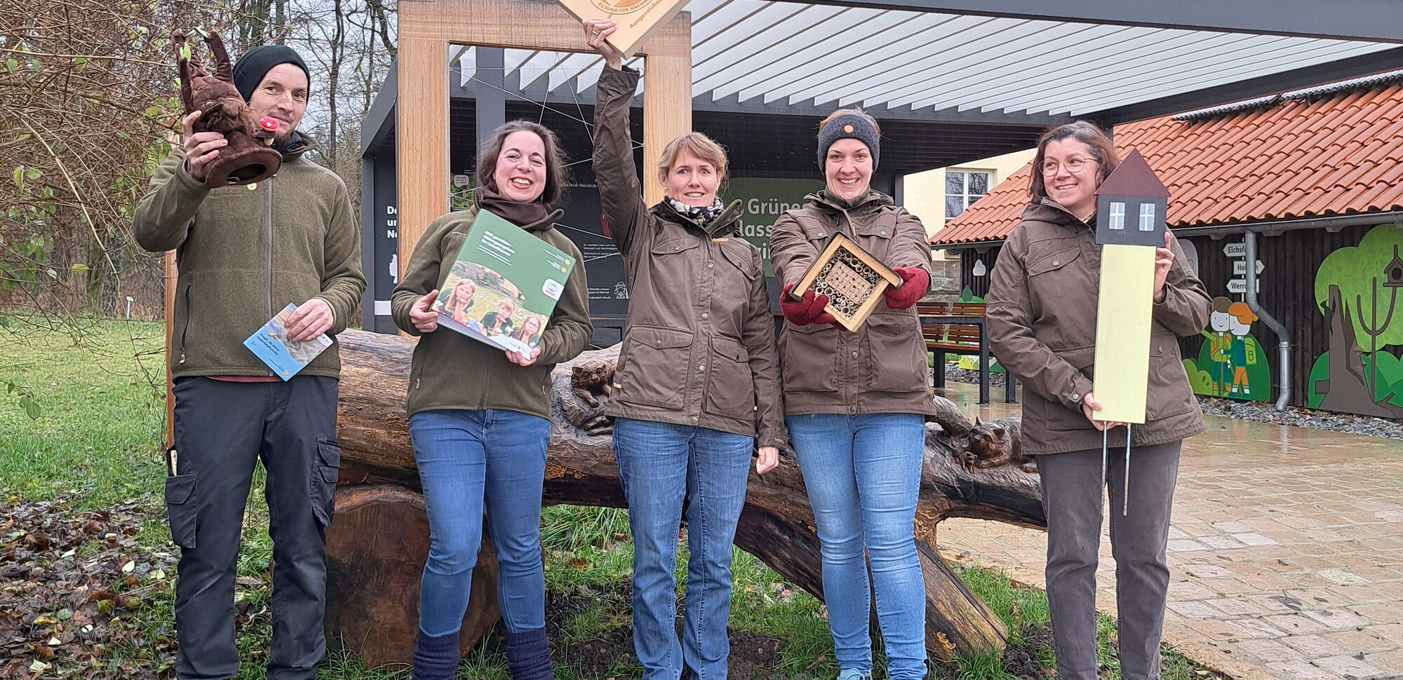 Eine Gruppe von fünf Mitarbeiter des Naturparks Eichsfeld-Hainich-Werratal posiert stolz mit dem Qualitätssiegel 'Bildung für nachhaltige Entwicklung' (BNE) vor dem Naturparkzentrum Fürstenhagen.