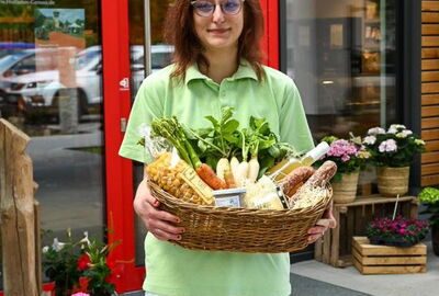 Eine Mitarbeiterin präsentiert einen großen Korb voller Spezialitäten aus dem Hofladen