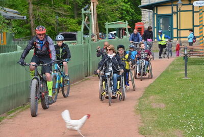 Sport, Barriere frei, Fitness, Streichelzoo, alter Bahnhof,
Auf dem Bild sind einige integrative Fahrrad Fahrer zu sehen. Im Vordergrund, rennt ein weißes Huhn durch das Bild.