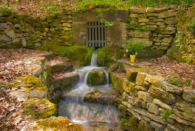 Kleiner Born in Fürstenhagen - Wasser fließt über Steinstufen umrahmt von Natursteinmauern