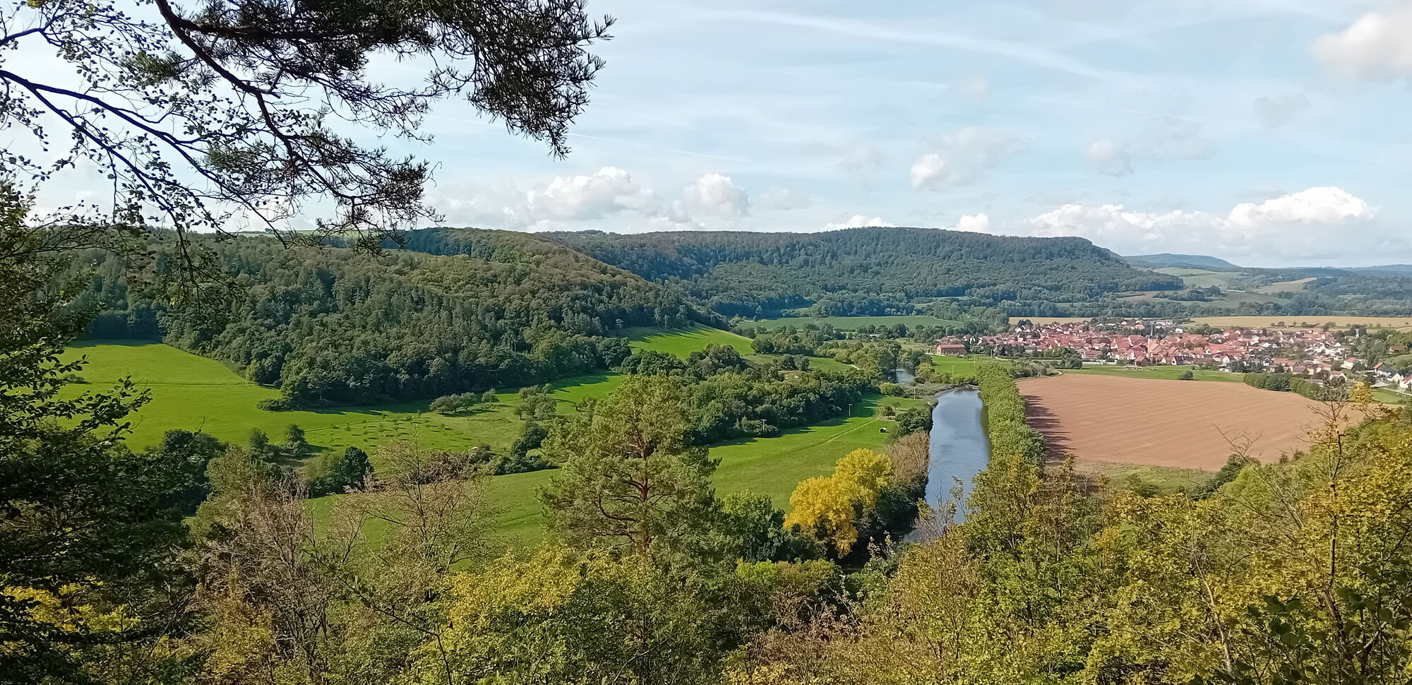Blick auf die Werra von einem erhöhten Punkt. Im Hintergrund der Ort Falken im Naturpark Eichsfeld Hainich Werratal.