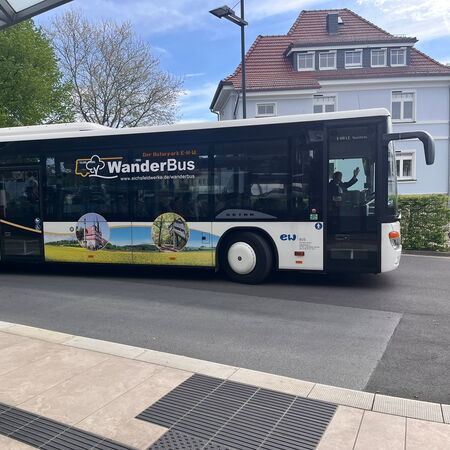 Ein Bus mit der Aufschrift "Wanderbus" fährt eine Straße entlang.