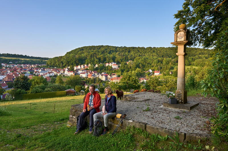 zwei Wanderer machen Pause am Bildstock oberhalb von Heyerode im Eichsfeld