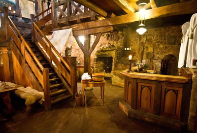 Urige Gaststube gemauerten W?nden und vielen Holzbalken. In der Mitte ist eine Holztreppe, die nach oben f?hrt. Im Hintergrund ein Kamin und eine Holztheke.