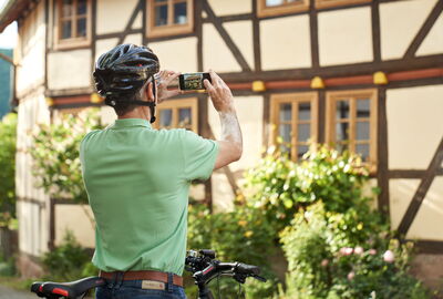 Radfahrer fotografiert ein Fachwerkhaus in Lindewerra