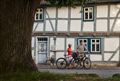 2 Radfahrer vor einem Fachwerkhaus im Werradorf Falken