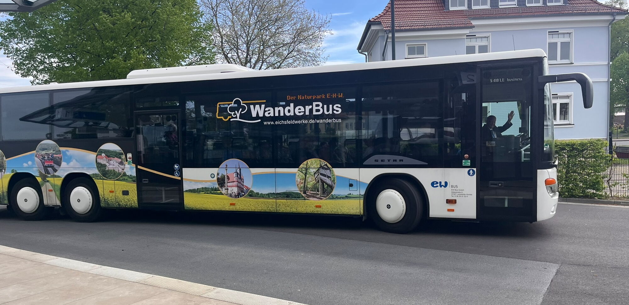 Ein Bus mit der Aufschrift "Wanderbus" fährt eine Straße entlang.