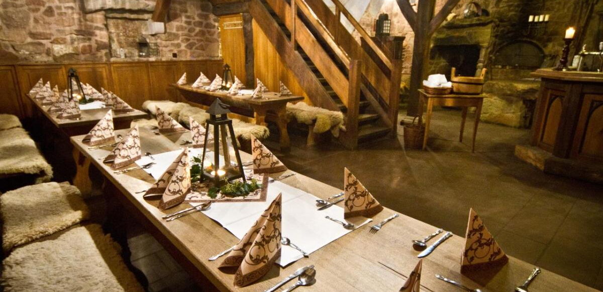 Urige Gaststube mit Holzvert?felung und gemauerten W?nden. Holztische mit B?nken, die mit Fell bedeckt sind. In der Mitte ist eine Holztreppe.?
