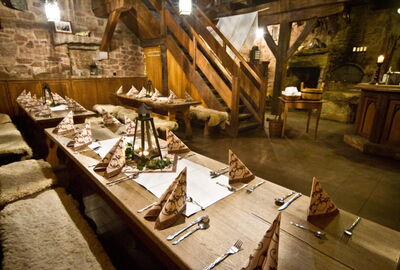 Urige Gaststube mit Holzvert?felung und gemauerten W?nden. Holztische mit B?nken, die mit Fell bedeckt sind. In der Mitte ist eine Holztreppe.?