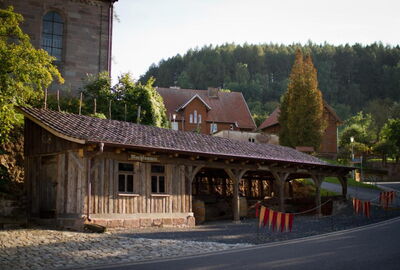 Blick auf die alte Remise au?erhalb der Gastst?tte. Ein Teil mit Holzw?nden ein Teil offen gestaltet mit Holzb?gen. Der gesamte Bereich ist ?berdacht.?