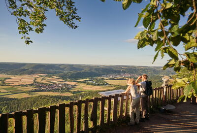 zwei Wanderer genießen die Aussicht vom Heldrastein ins Werratal