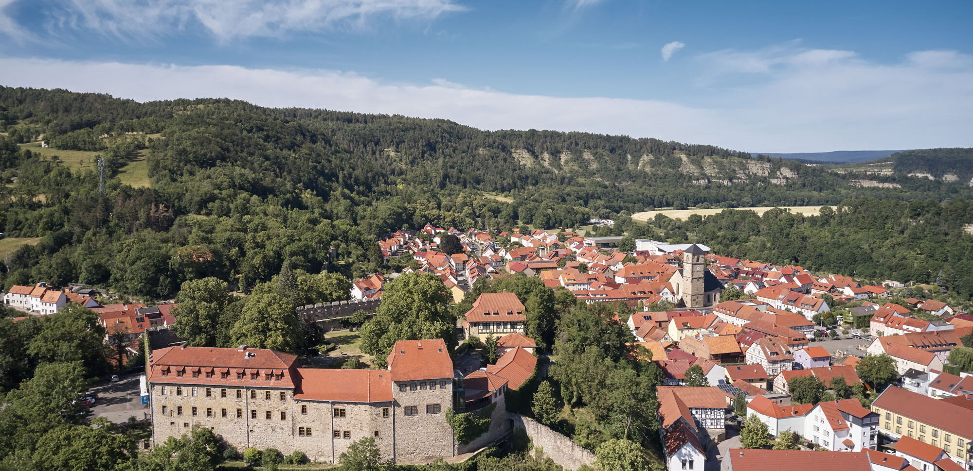 Blick auf Creuzburg mit der gleichnamigen Burg im Vordergrund. Im Hintergrund sind die Felsen der Ebenauer Köpfe zu sehen.